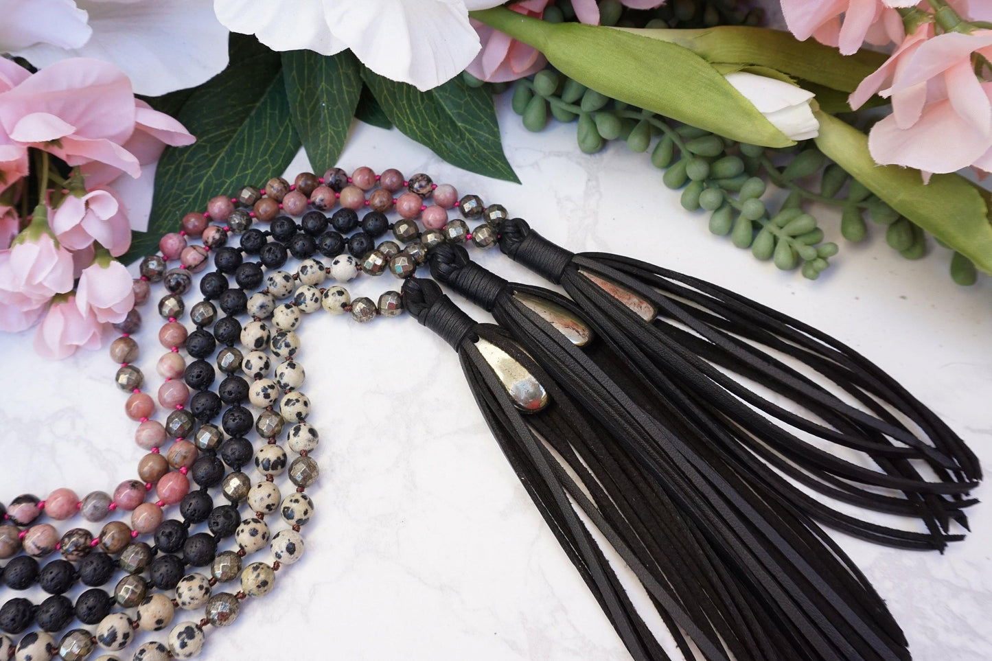 Modern Crystal Mala Necklace featuring natural crysta beads and vegan black faux leather tassels. Pyrite crystal accents that allow you to carry your natural protective crystal energies with style.